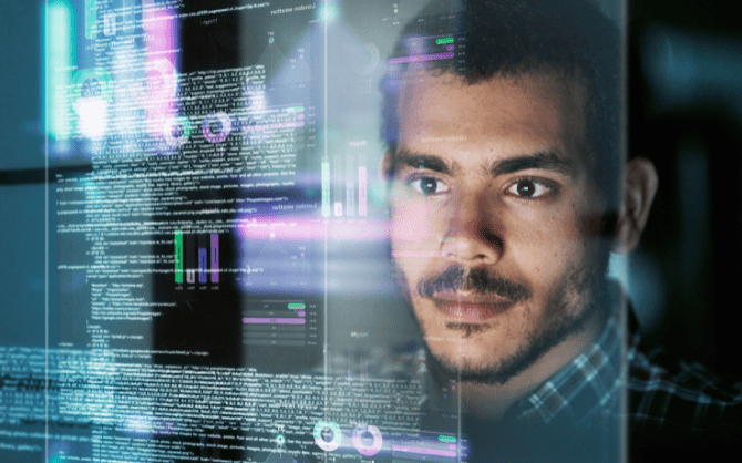 man looking at a screen software code and charts