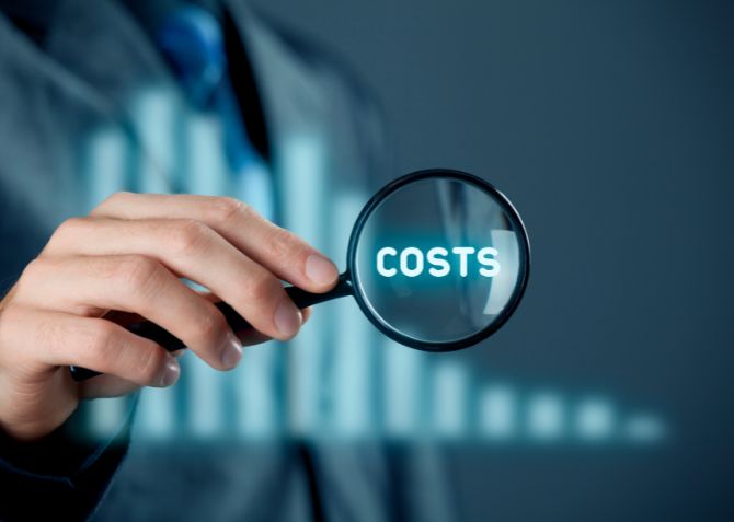 costs with magnifying glass and a background chart - reducing costs is the base of lean manufacturing principles