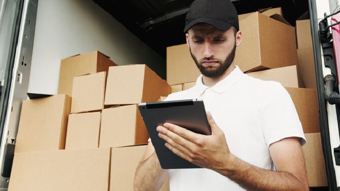 A man looking at his tablet, thinking about how to choose the best shipping carrier. 
