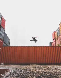 A man jumping over shipping containers.