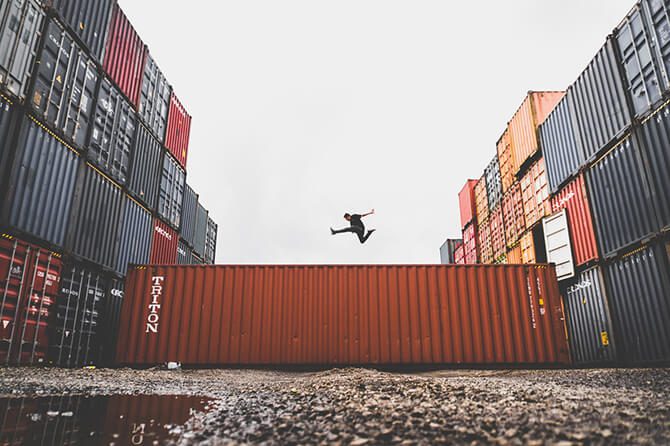 A man jumping over shipping containers.
