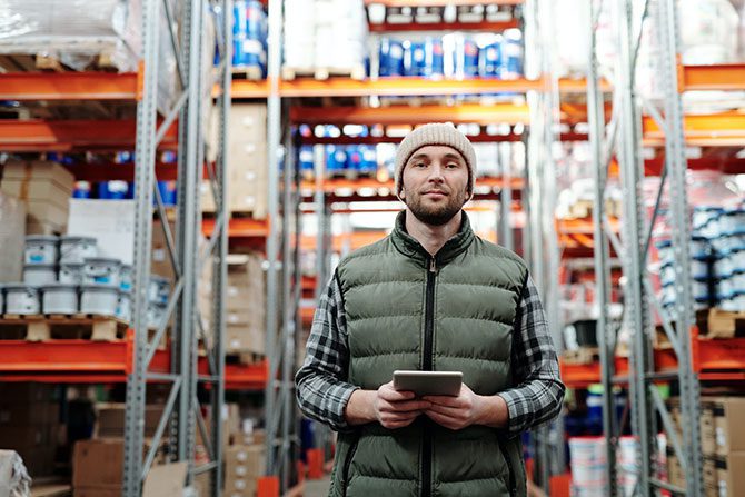 A man with a notepad standing in a warehouse