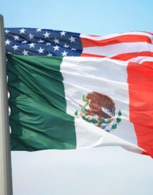 Flags of Mexico and the United States waving together, symbolizing the trade relationship and the impact of the 2025 tariffs.