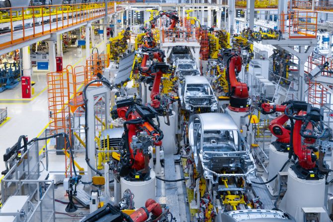 Automobile assembly line with robotic arms manufacturing vehicles, representing Mexico's automotive industry and its reliance on U.S. exports.