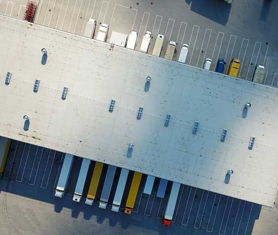 Aerial view of a logistics warehouse with multiple freight trucks docked, representing large-scale supply chain operations and distribution efficiency.