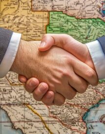 business handshake in front of a map, symbolizing cross-border logistics or international business partnership.