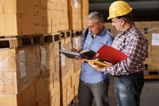 Two logistics professionals discussing inventory management in a warehouse, symbolizing collaboration with a cross-border logistics provider.