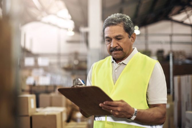 a mexican worker checking some papers in a warehouse